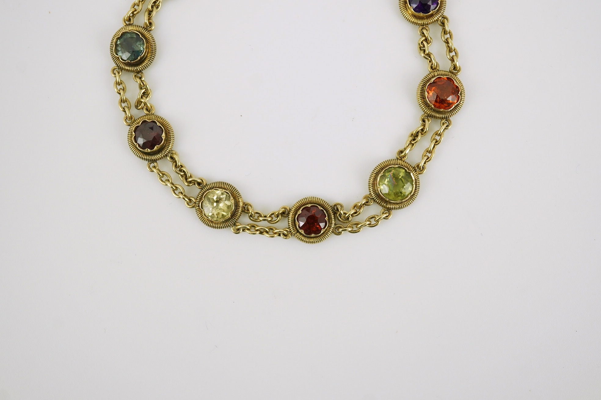 An early 20th century yellow metal and ten stone multi gem set chain link bracelet